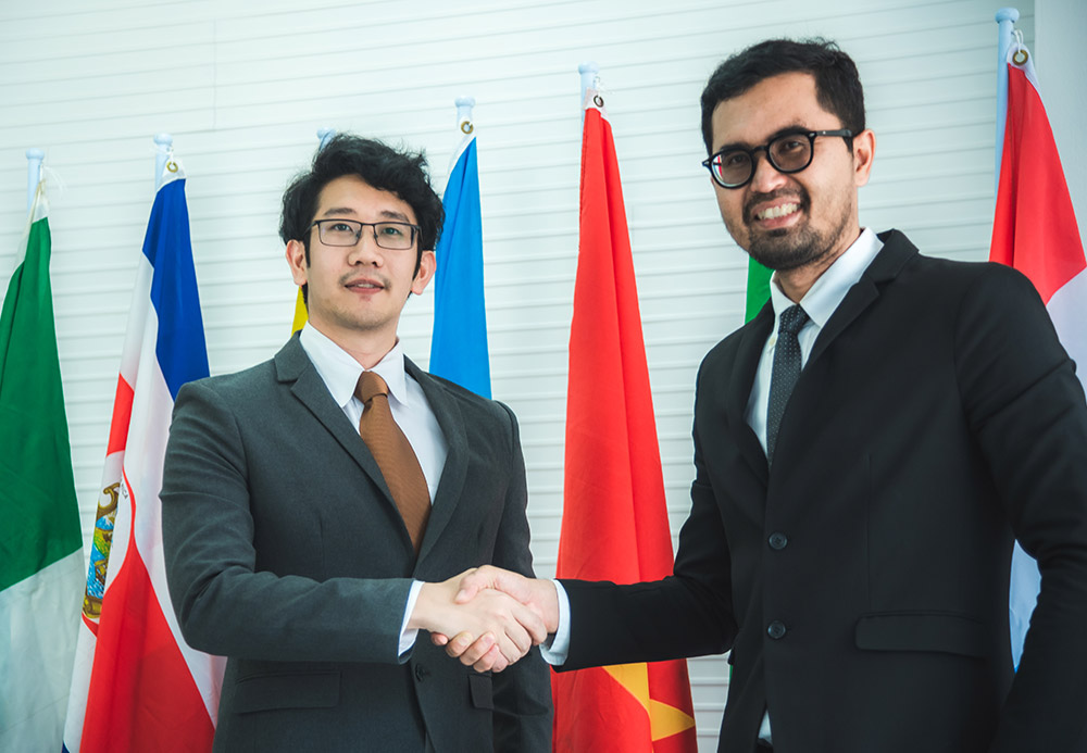 business-people-shake-hands-international-flag-bac-XY8PTZ2