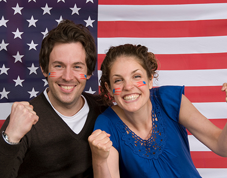 couple-smiling-with-american-flag-TYEU6LR